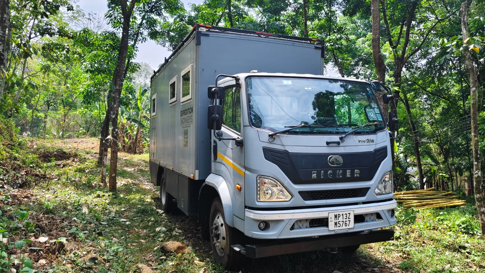 The expedition truck set up in a forest clearing, surrounded by green canopy.