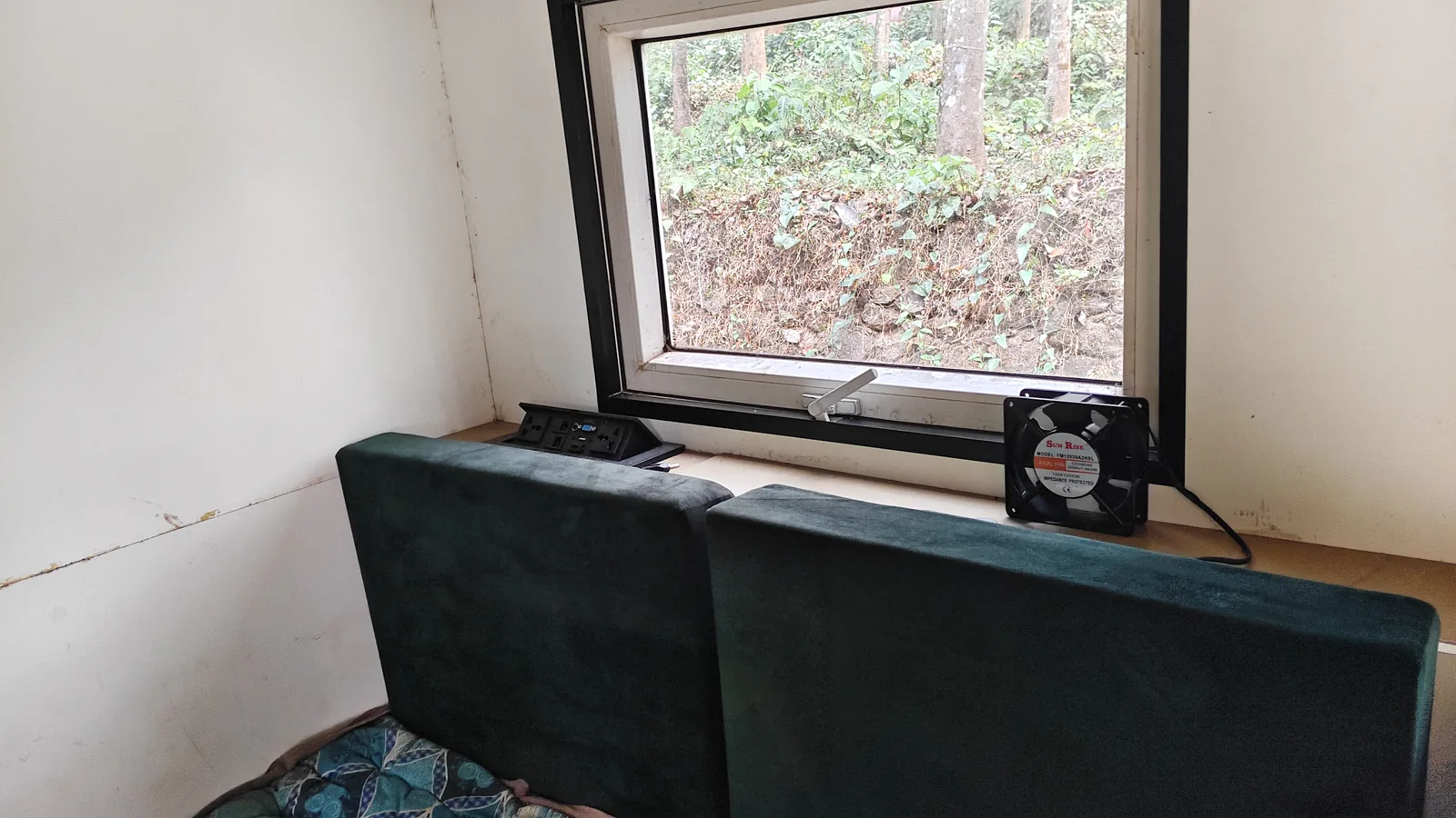 Upholstered lounge seating beneath a large side window inside the habitat.