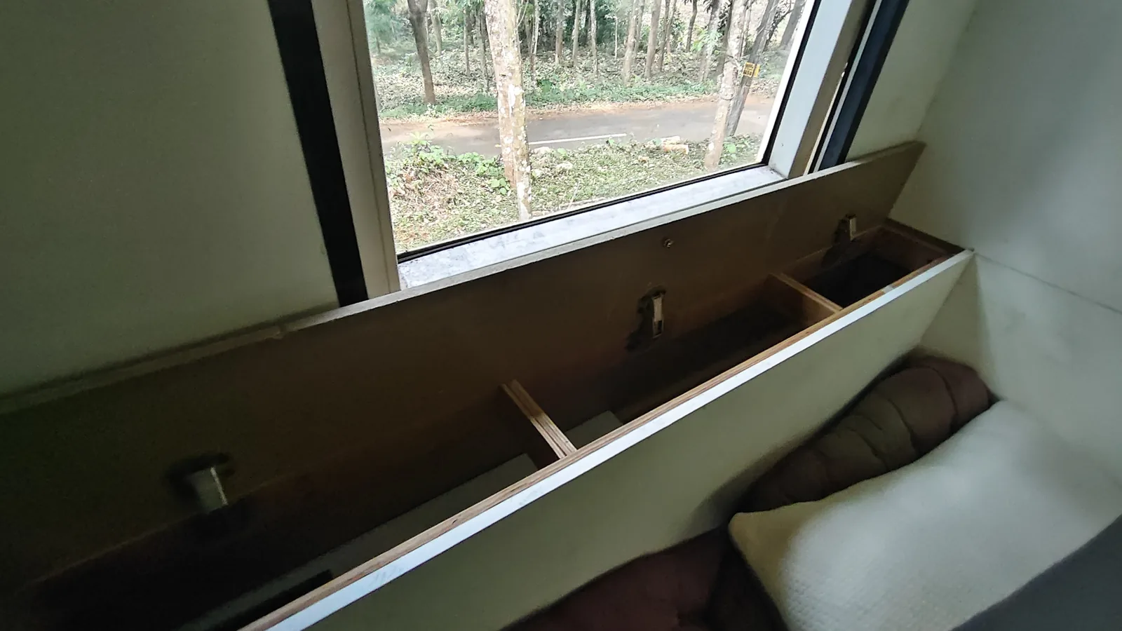 The lounge bench with cushions looking out over forest through a long side window.